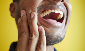 Man with hand on jaw showing signs of jaw discomfort