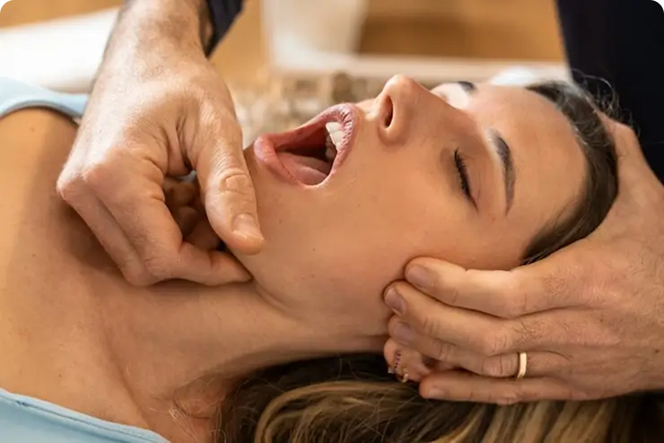 Dentist performing muscle relaxation therapy on a patient's jaw