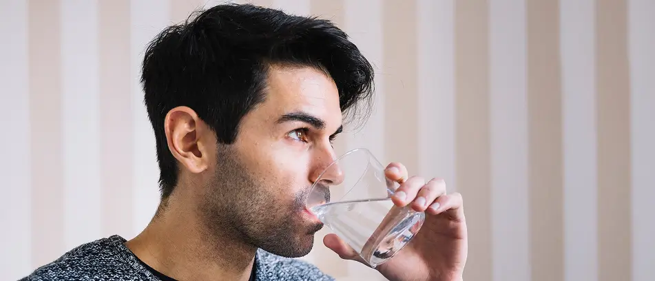 Person drinking water to help prevent tooth decay and cavities